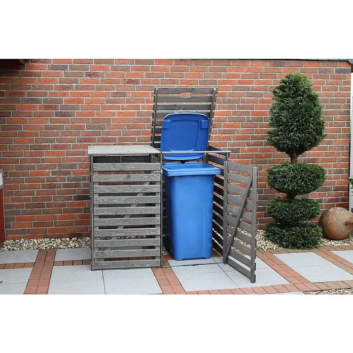Promadino Mülltonnenbox Vario V -  - Mülltonnenbox mit einer geöffneten blauen Mülltonne vor einer roten Backsteinmauer und einer kleinen immergrünen Pflanze.