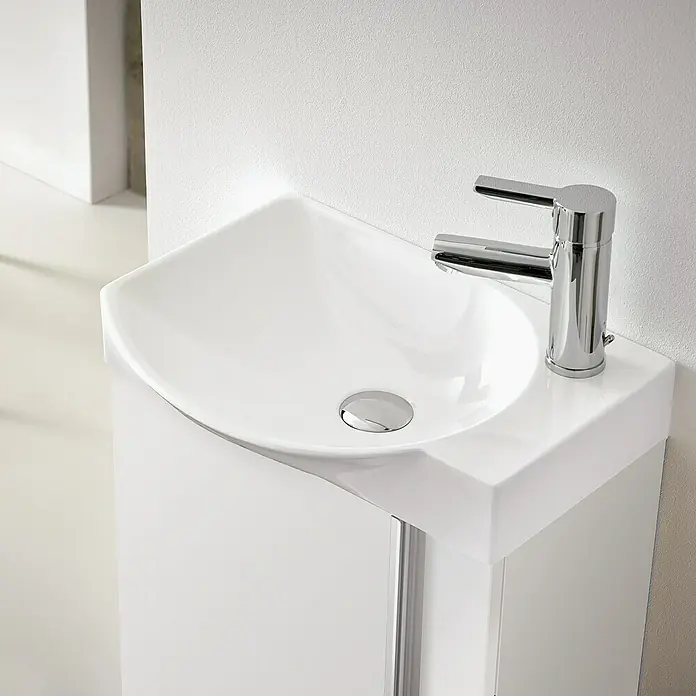 Riva Badmöbel-Set Elegance - Gesamtbreite Badmöbel: 45,2 cm, Weiß glänzend - Nahaufnahme eines modernen, weißen Waschbeckens mit verchromtem Wasserhahn, das ein elegantes und minimalistisches Baddesign zeigt.