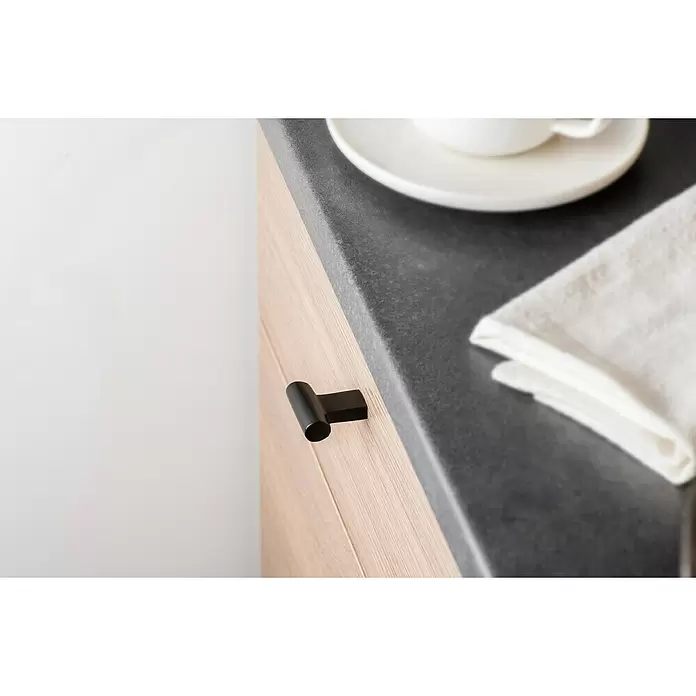 Rei Pomo para muebles - Ø x L: 12 x 33 mm, Negro - Tirador negro en un mueble de cocina de madera clara, junto a una encimera gris oscuro.