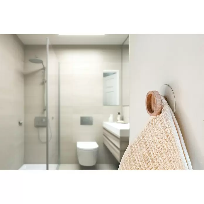 Rei Garderobenhaken C8717 - L x B x H: 26 x 60 x 60 mm, Holz, Weiß - Hölzerner Handtuchhaken hält ein helles, strukturiertes Handtuch an der Wand in einem unscharfen modernen Badezimmer.