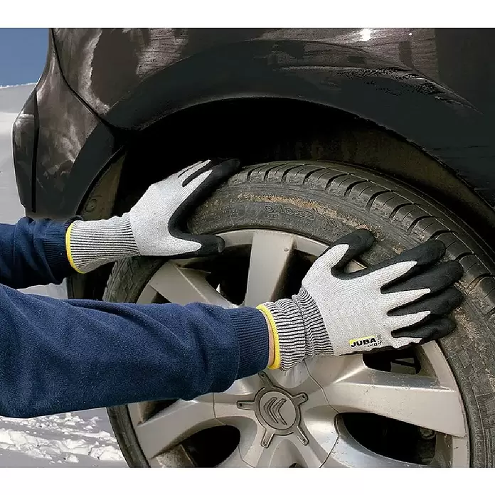 Juba Guantes de trabajo H4117 - Talla del guante: 7, Gris/Negro, 2 ud. - Guantes protectores grises y negros con puño amarillo, manejando un neumático de coche en la nieve.