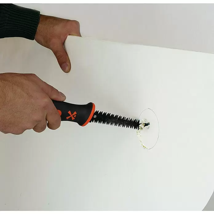 Mondelin Gipskartonplatten-Stichsäge - Länge: 160 mm - Eine Person schneidet mit einer Handsäge mit schwarz-orangem Griff ein rundes Loch in eine weiße Platte.
