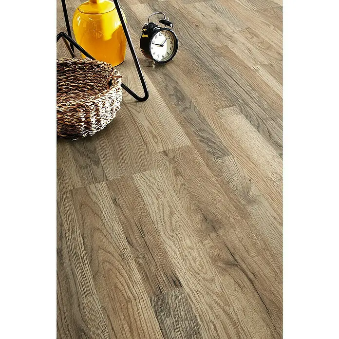LOGOCLIC Silentos Laminatmuster Eiche Cabino - 300 x 192 x 9 mm, Landhausdiele - Ein stilvolles Bild von Holzbodenplatten, ergänzt durch eine gelbe Dose, einen Korb und eine schwarze Uhr, die das Ambiente des Raumes unterstreichen.