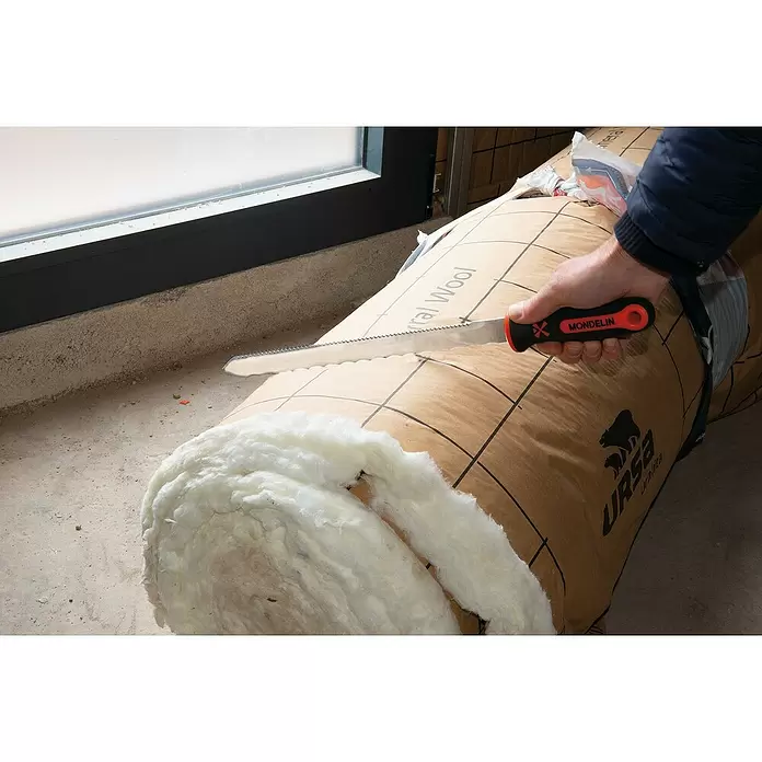 Mondelin Dämmstoffmesser - Länge: 280 mm - Hand hält ein rot-schwarzes gezahntes Isolationsmesser von Mondelin, das eine Mineralwollerolle schneidet.