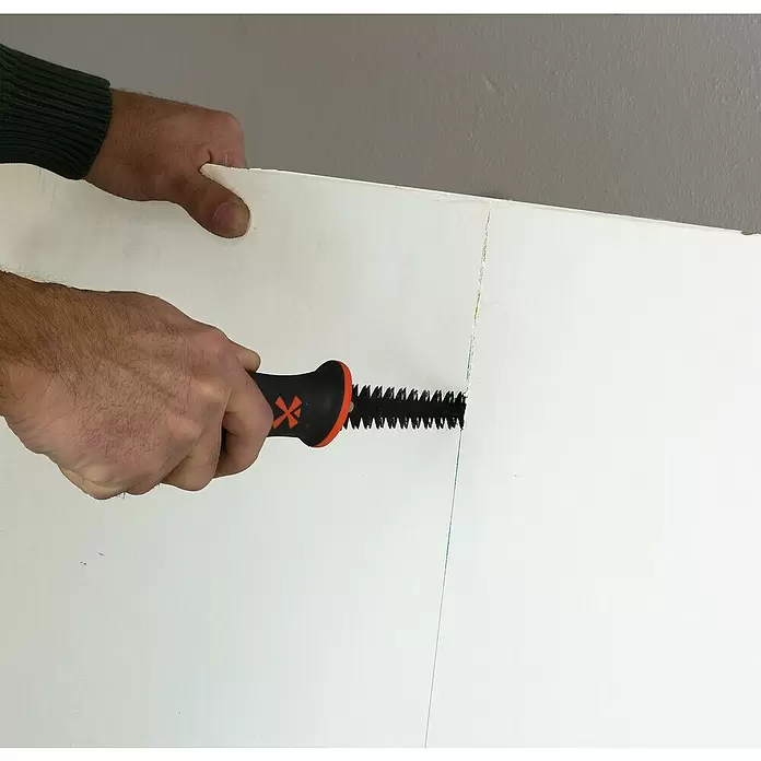 Mondelin Gipskartonplatten-Stichsäge - Länge: 160 mm - Person schneidet mit einer orange-schwarzen Trockenbausäge eine weiße Platte.