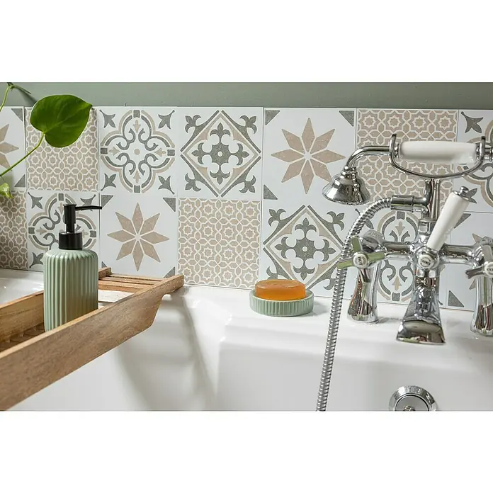 D-c-fix Fliesensticker Wall Tiles Jamila - 6 Stk., 15 x 15 cm, Olive - Nahaufnahme einer Badewanne mit Armatur, Seife und einem hölzernen Badewannen-Caddy mit einer grünen Seifenpumpe, vor einem Hintergrund aus gemusterten Fliesen.