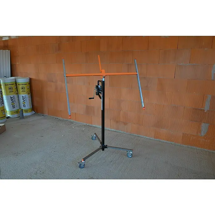 Plattenlift Mondelin Easylev - Höhenverstellung: 150 cm - 310 cm - Eine Gipskartonplatten-Hebebühne, die für die Montage von Gipskartonplatten an Wänden und Decken verwendet wird. Sie steht vor einer Ziegelwand.