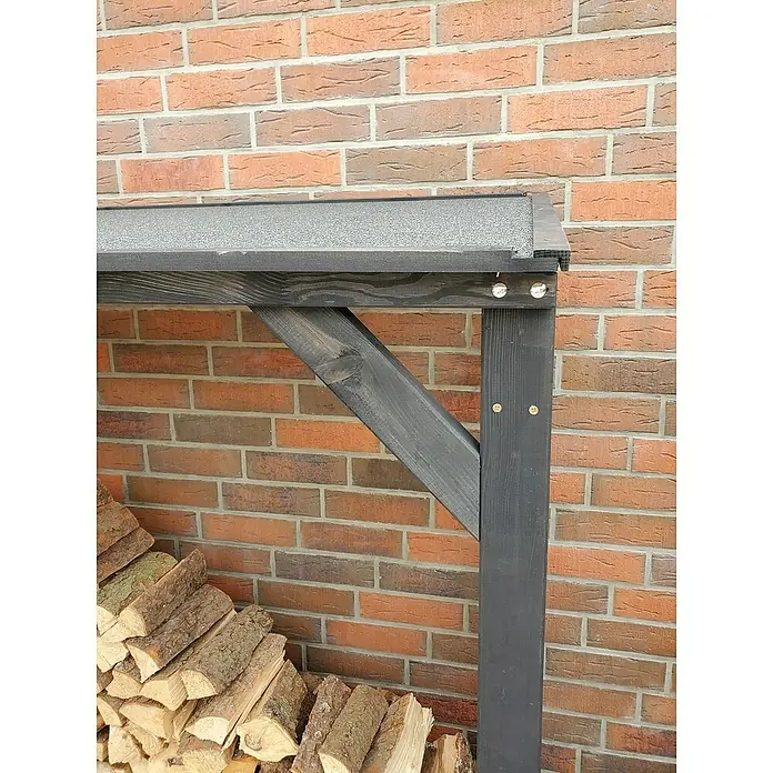 Promadino Kaminholzregal Speyer - 120 x 68 x 148 cm, Holz, Anthrazit - Nahaufnahme eines dunklen Holzregals für Brennholz, das an einer Ziegelwand lehnt und mit Holzscheiten gefüllt ist.