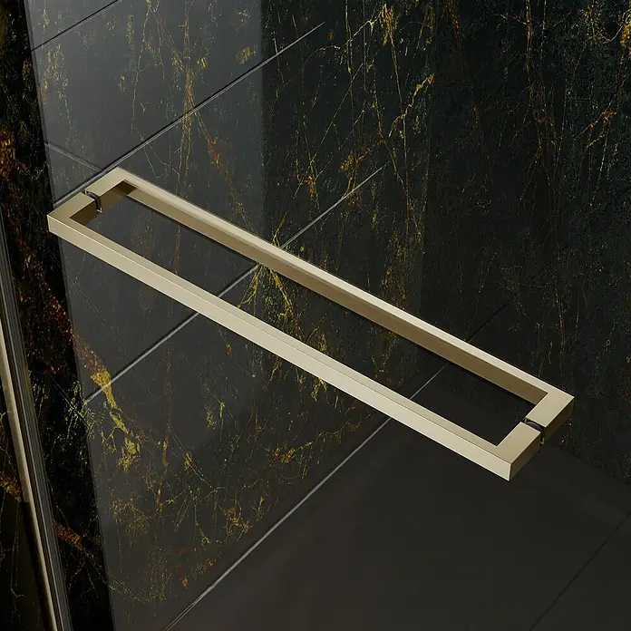 Camargue Palermo Beschlag-Set B - Brushed Gold, Einbauart: Ecke - Nahaufnahme eines modernen, rechteckigen, goldenen Handtuchhalters vor einem Hintergrund aus dunklen, marmorierten Fliesen.