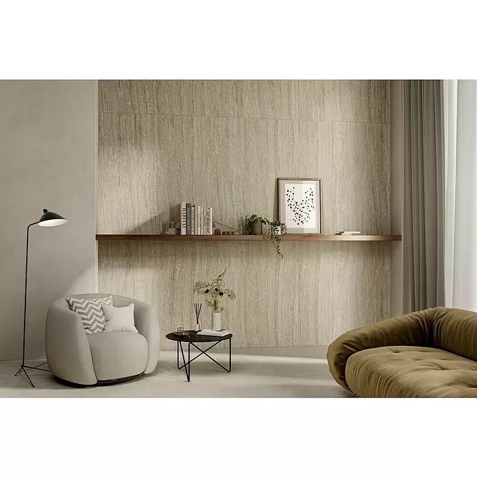 Corso Italia Feinsteinzeugfliese Traventino - 120 x 278 cm, Beige, Matt - Hellbraune Wandfliesen in Travertin-Optik mit vertikalen Wellenmustern, als Akzentwand in einem modernen Wohnzimmer mit schwebendem Regal installiert.