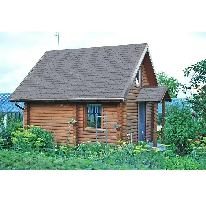 Bitumendachbahn KSK Plus - Grau, 5 x 0,33 m, Selbstklebend, Rechteckig - Gemütliches Blockhaus mit grauem Dach und blauer Tür, umgeben von üppigem Grün.