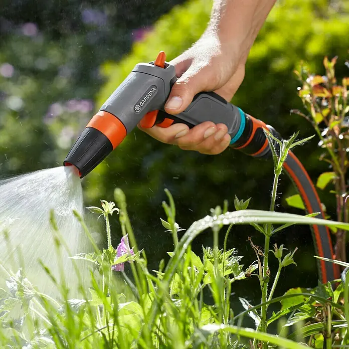 Gardena Comfort Reinigungsspritze - Anzahl Sprühformen: 2 Stk., Kunststoff - Nahaufnahme einer Gardena-Gartenspritze in Aktion, die Wasser auf Pflanzen sprüht. Perfekt für die Gartenbewässerung und Pflanzenpflege.