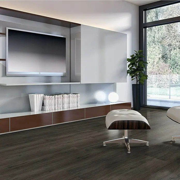 Vinylboden Sly 1:2:3 - Cambridge Oak, Mehrstab - Elegantes Wohnzimmer mit dunklem Holzboden, modernem TV-Möbel und stilvollem Sessel mit Fußhocker, der den Fokus auf das luxuriöse Bodendesign legt.