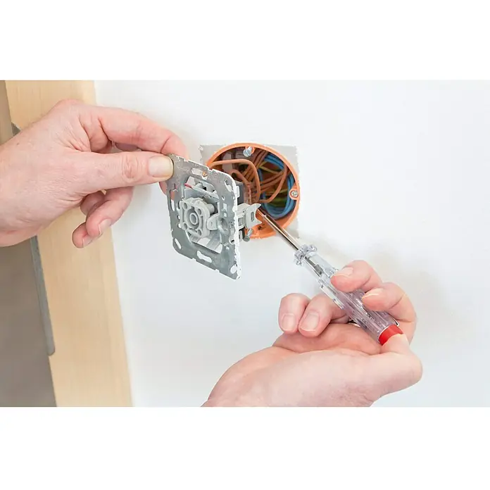 Hazet Spannungsprüfer 839-1 - Klingenlänge: 40 mm - Ein Elektriker arbeitet an einer Steckdose mit einem Schraubendreher, um die elektrische Installation zu überprüfen. Sichere Elektroinstallationen sind wichtig.