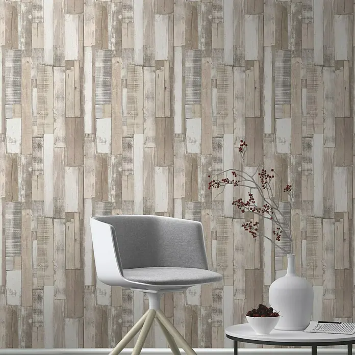 Rasch Papiertapete - Beige/Creme, Holzoptik, 10,05 x 0,53 m - Nahaufnahme eines Raumes mit einer Holzwandtapete, einem grauen Stuhl und einem weißen Beistelltisch mit Dekorationen.