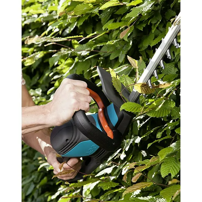Gardena ComfortCut Elektro-Heckenschere 550/50 - 550 W, Schnittlänge: 50 cm, Max. Aststärke: 27 mm - Nahaufnahme einer Person, die mit einer Gardena Heckenschere eine Hecke schneidet.