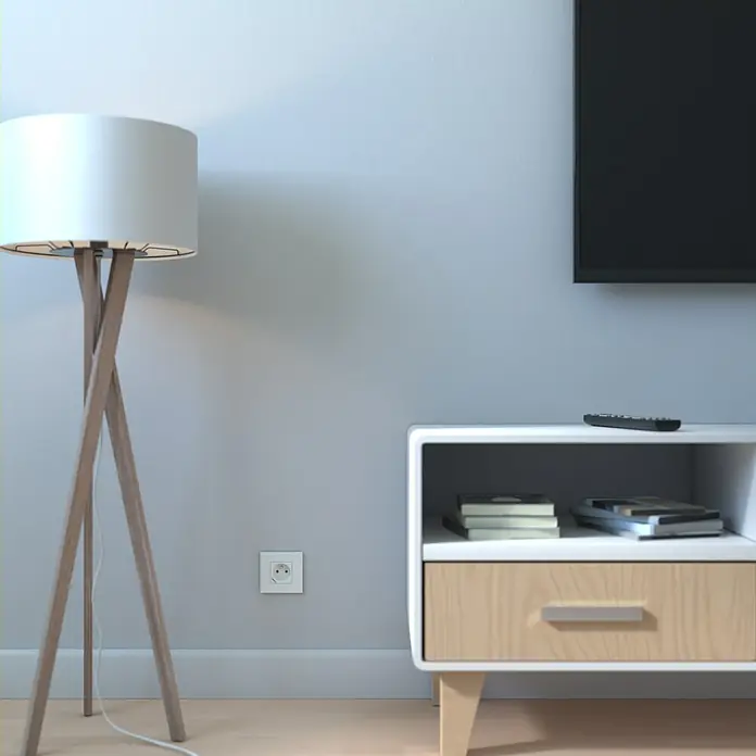 Schneider Electric New Unica Marco - Gris cava, Plástico, Colocar - Esta imagen muestra una lámpara de pie moderna con base de madera y pantalla blanca, junto a una mesita de noche blanca con cajón de madera.