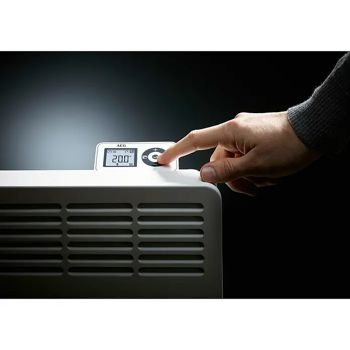 AEG Konvektorheizung Wandmontage - 500 W, Raumheizvermögen: 6 m², Alpinweiß - Nahaufnahme eines weißen AEG Heizkörpers mit digitaler Temperaturanzeige, eine Hand drückt einen Knopf zur Einstellung.