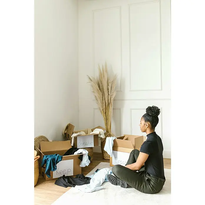 BAUHAUS Caja de embalaje Multibox XXL - L x An x Al: 72,5 x 41 x 44 cm, Capacidad de carga: 30 kg, 1 ud. - Una mujer está sentada en el suelo rodeada de cajas etiquetadas para 'guardar', 'donar' y 'basura' mientras clasifica ropa.