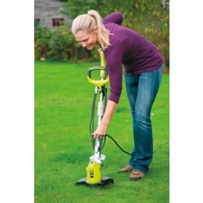 Ryobi Recortabordes eléctrico RLT6030 - 600 W, Ancho de corte hilo: 30 cm - Una mujer usa un cortabordes amarillo y negro en el jardín. El cortabordes se usa para recortar bordes.