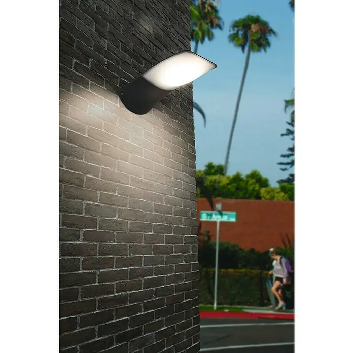 Lutec Aplique exterior LED Zerta - 30 W, 30,3 x 20 x 14,3 cm, Antracita, Opal, IP44 - Aplique de pared de ladrillo que ilumina una calle con peatones y palmeras al fondo. El diseño moderno se integra bien en su entorno.