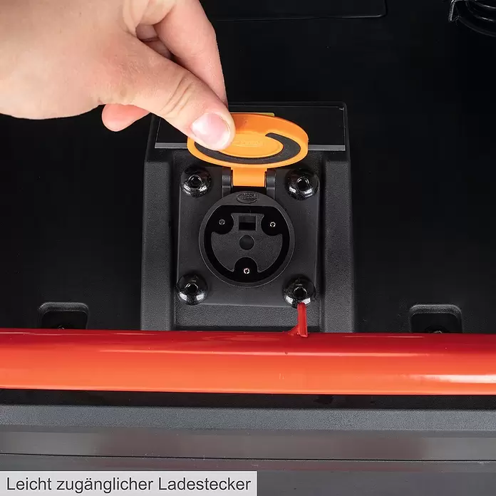 Scheppach Akku-Aufsitzmäher MR920-E - 48 V, 75 Ah, Schnittbreite: 92 cm, Max. Flächenempfehlung: 2.000 m² - Hand öffnet orange Klappe eines schwarzen YEERDA Ladeanschlusses.