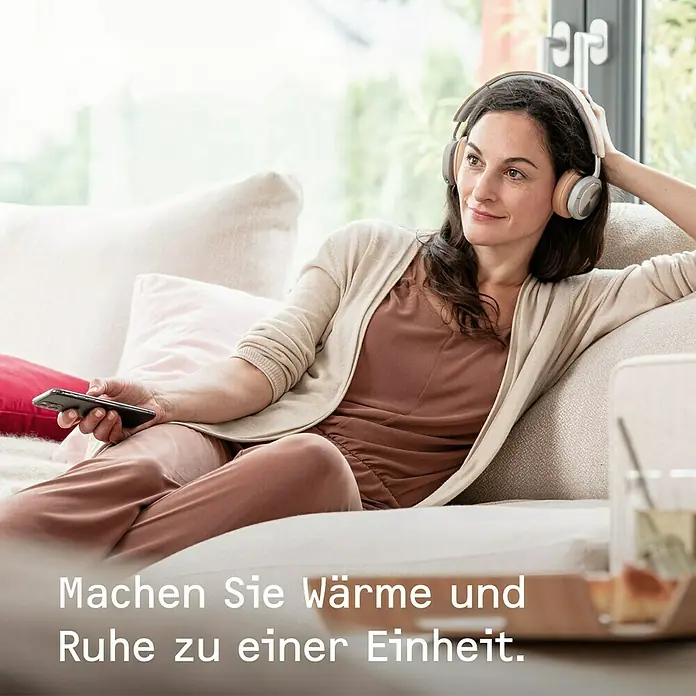 Stiebel Eltron Konvektorheizung EG-50-PL2-PE - 2.000 W, Raumheizvermögen: 25 m², Weiß - Frau entspannt mit kabellosen Kopfhörern auf dem Sofa.