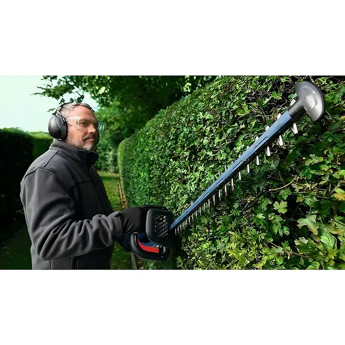 Bosch Professional AMPShare 18V Akku-Heckenschere GHE 18V-60 II - 18 V, Ohne Akku, Schwertlänge: 60 cm - Ein Mann benutzt eine Heckenschere, um eine grüne Hecke zu trimmen. Der Fokus liegt auf der Heckenschere und dem Mann mit Schutzausrüstung.