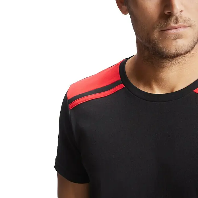 Camiseta Expedition - S, Negro/Rojo, 60% algodón / 40% poliéster - Primer plano de un hombre que lleva una camiseta negra con detalles rojos en el hombro. La camiseta destaca estilo y comodidad.