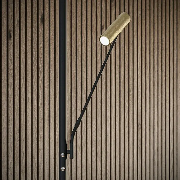 Tween Light LED-Stehleuchte Orlando - Höhe: 180 cm, Sandschwarz, Messing gebürstet, Warmweiß - Nahaufnahme einer modernen, goldenen Wandleuchte mit flexiblem Arm vor einer Holzwand.