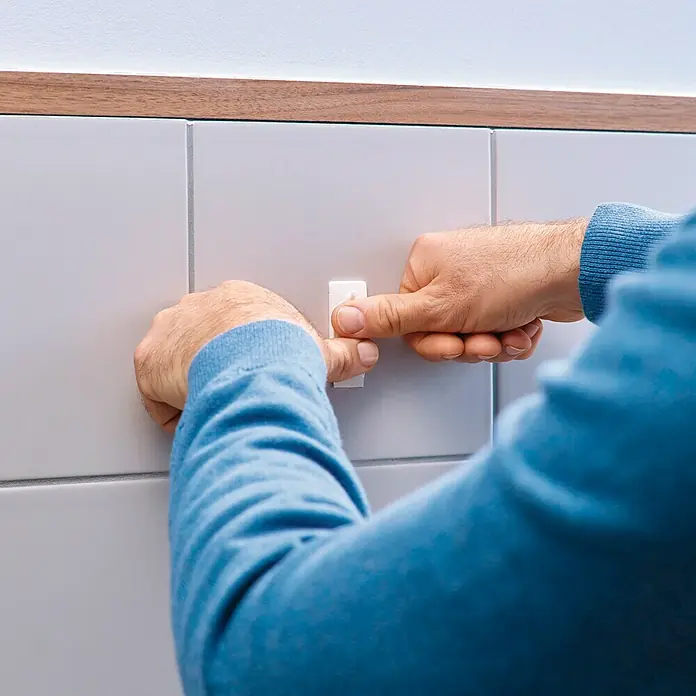 Tesa Clavo adhesivo - Blanco, Carga soportada: 2 kg, 2 ud., Azulejos - Alguien pega un gancho blanco autoadhesivo a una pared de azulejos. Es de plástico y apto para baños.