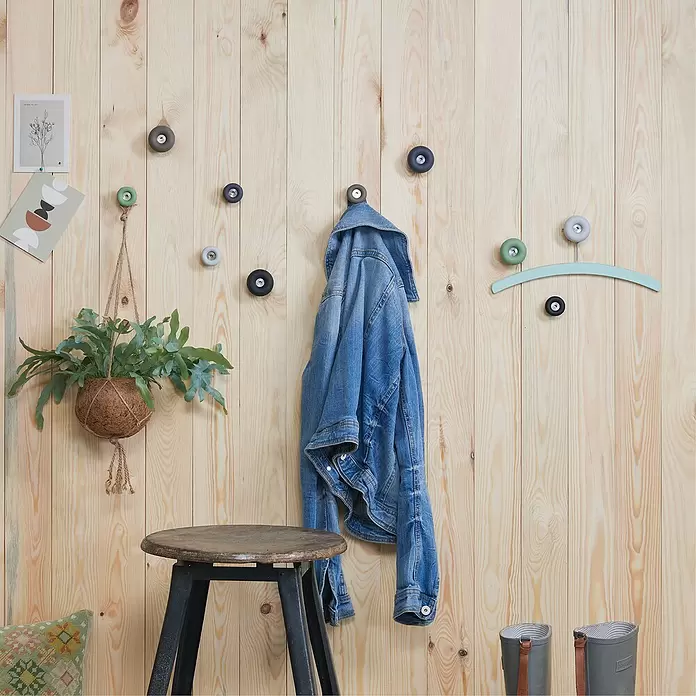 Wagner System Garderobenhaken DOT - Ø x H: 50 x 30 mm, Lichtgrau, 1 Stk. - Runde, farbenfrohe Wandhaken in verschiedenen Farbtönen an einer Holzwand, halten eine Jeansjacke und eine Pflanze.