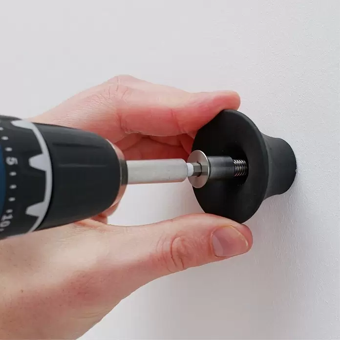 Wagner System Garderobenhaken - Ø x H: 40 x 25 mm, Schiefergrau, 1 Stk. - Hand schraubt mit Bohrmaschine eine schwarze, tassenförmige Wandhalterung.