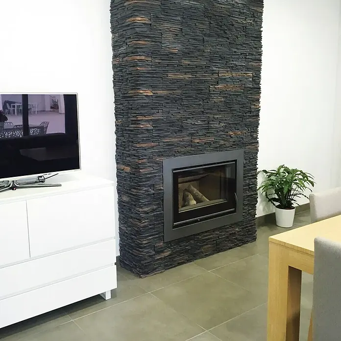 Esquina exterior Galicia PIzarra - 20 x 12,5 x 10 cm, Antracita - Chimenea revestida de piedra con hogar encastrado en un salón de estar amueblado de forma moderna. Un elemento elegante y cálido para el hogar.