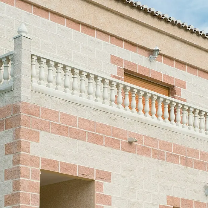 Pasamano Palermo - Hormigón - Fachada de un edificio con barandilla de balcón decorativa y revestimiento de piedra clara en tonos rosa y beige para un aspecto elegante.