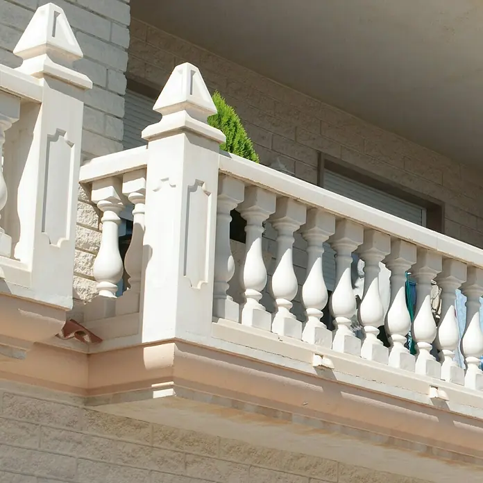 Columna decorativa Milan 1 - 20 cm x 1 m, Blanco - Primer plano de una barandilla de balcón decorativa blanca con balaustradas, que acentúa la arquitectura del edificio.