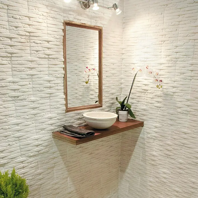 Revestimiento de piedra Listelo Hueso - 28 x 14 x 1 cm - Elegante baño con lavabo sobre estante de madera, espejo y pared de ladrillo blanco para un toque moderno.