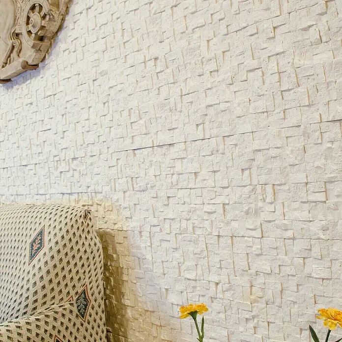 Revestimiento de piedra Trencadis Hueso - 30 x 15 x 2 cm - Primer plano de una elegante pared con revestimiento de piedra blanca, que ofrece una textura moderna y un elemento decorativo para el interior.