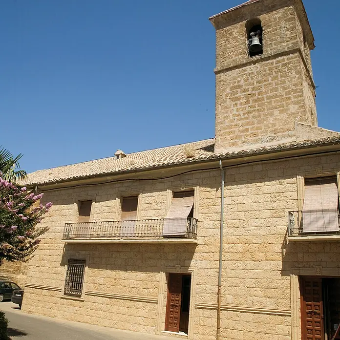 Revestimiento de piedra Coral Piedra - Coral - Antigua iglesia de piedra con campanario y persianas marrones bajo un cielo azul.