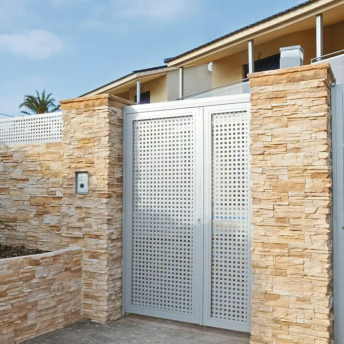 Moldura decorativa Petra Arena - 75 x 11 x 6 cm - La imagen muestra una puerta de entrada elegante y moderna con aberturas cuadradas, enmarcada por muros de piedra decorativa.