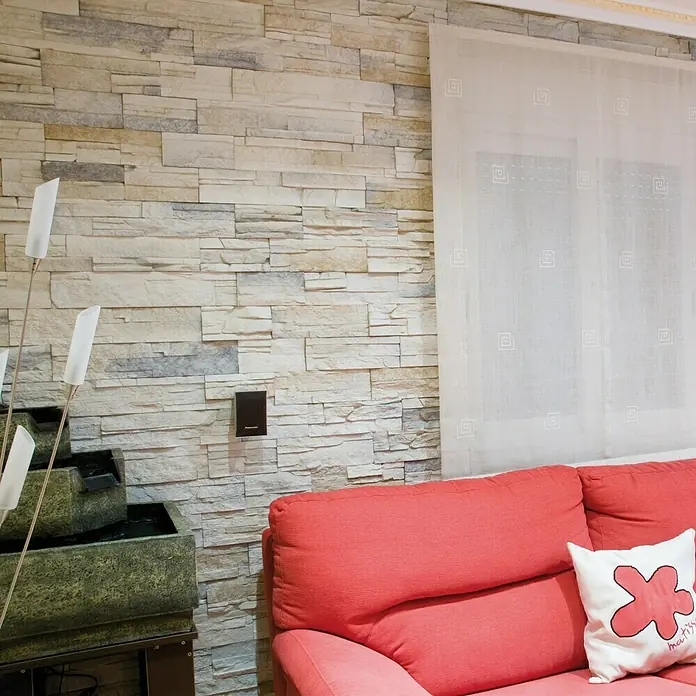 Revestimiento de piedra Petra Cuarzo - Cantidad total: 4 pzs., Cuarzo - Una sala de estar acogedora con un sofá color coral y un cojín decorativo, que crea un espacio invitante para la relajación.
