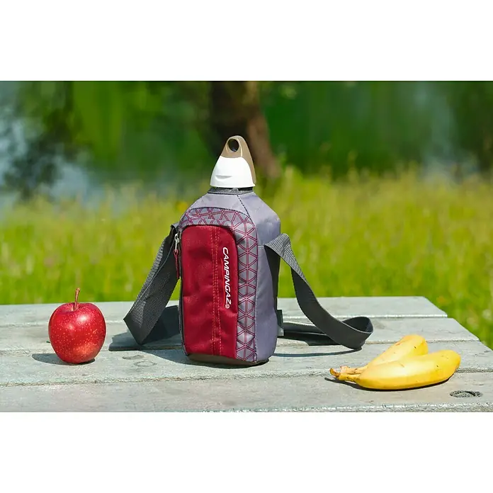 Campingaz Botella térmica Flex Picnic - Capacidad volumétrica: 1 l, Gris - Primer plano de una botella de agua CampinGaz en un bolso, acompañada de una manzana y plátanos, ideal para aventuras al aire libre.