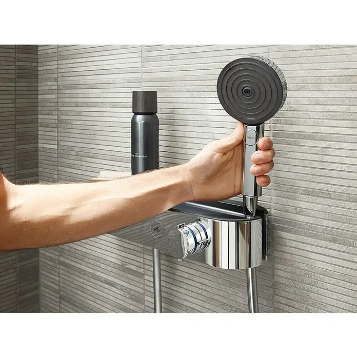 Hansgrohe Pulsify Select S Handbrause 105 Relaxation EcoSmart - Anzahl Funktionen: 3 Stk., Durchmesser: 10,5 cm, Chrom - Nahaufnahme einer Hand, die einen Hansgrohe Duschkopf hält, der an einem Thermostat mit Ablage befestigt ist. Elegantes Baddesign.