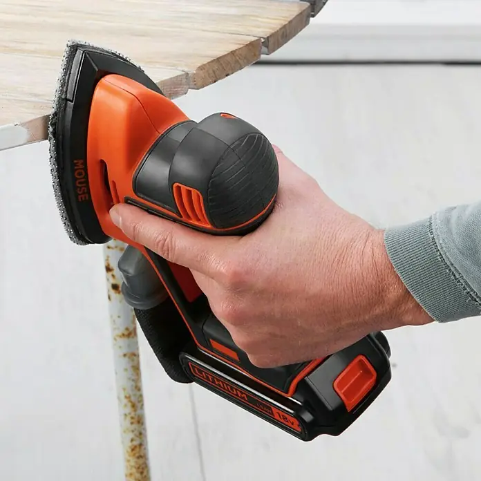 Black+Decker Lijadora delta de batería BDCDS18 - 18 V, 1 batería, 1,5 Ah - Primer plano de una lijadora Mouse de Black+Decker en uso sobre una superficie de madera, con la batería visible.