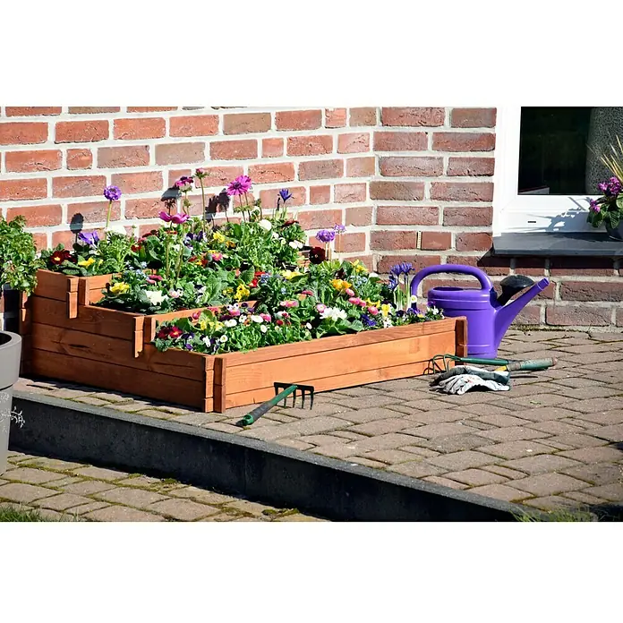 Dobar Hochbeet Peru - 110 x 88 x 36 cm, Holz, Bernstein - Hochbeet aus Holz mit bunten Blumen, Gießkanne und Gartengeräten vor einer Ziegelmauer. Ideal für den Garten oder Balkon.