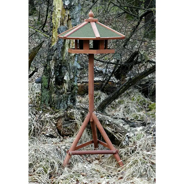 Dobar Vogelhaus Panorama - 66 x 66 x 140,5 cm, Grün/Braun, Holz - Dieses Bild zeigt ein rustikales, hölzernes Vogelhaus mit einem pyramidenförmigen Dach, das auf einem Ständer inmitten einer natürlichen Umgebung steht.