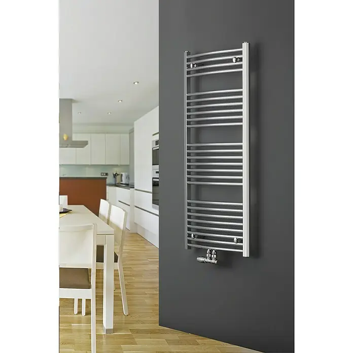 Ximax Badheizkörper C2 - B x H: 600 x 916 mm, Wärmeleistung bei Vorlauftemperatur von 75 °C (D: 50): 315 W, Anschlusskombination Heizkörper: Mittig unten - Ein moderner, silberner Handtuchwärmer ist an einer grauen Wand befestigt und bietet effiziente Wärme für jedes Badezimmer.