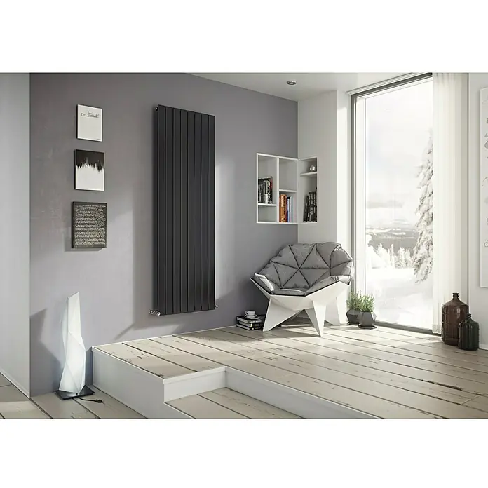 Ximax Raumheizkörper P1 - B x H: 595 x 1.800 mm, Wärmeleistung bei Vorlauftemperatur von 75 °C (D: 50): 1.144 W, Anthrazit - Ein modernes Interieur mit einem grauen, vertikalen Heizkörper, der an einer grauen Wand hängt. Das Design wird durch zeitgenössische Kunst und Möbel ergänzt.