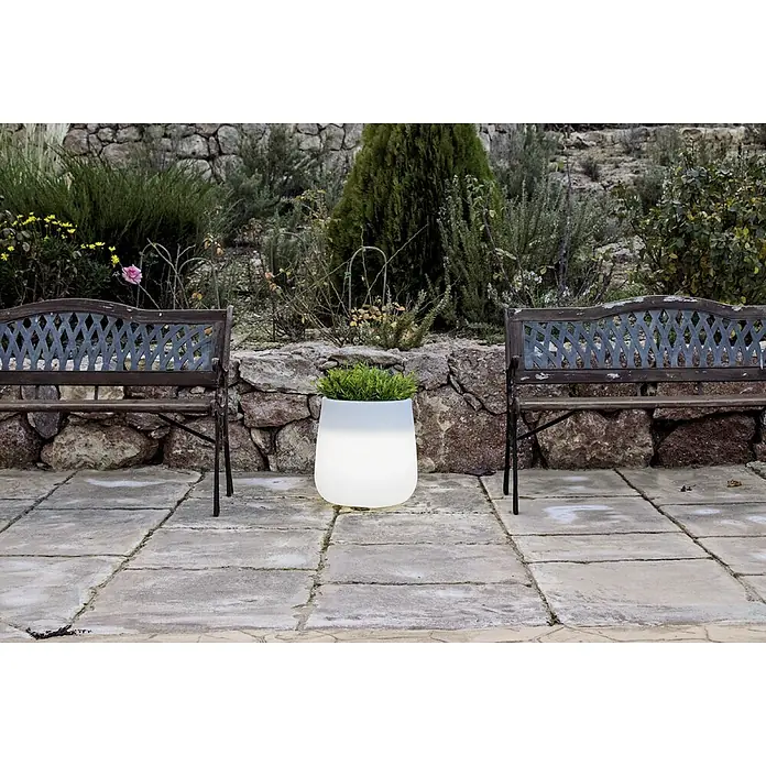 New Garden LED-Blumentopf Camelia - 8 W, Höhe: 40 cm - Leuchtender Pflanztopf mit grünen Pflanzen steht zwischen zwei Bänken im Freien und sorgt für eine angenehme Atmosphäre.