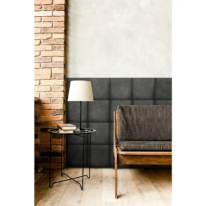 Fllow Wandpolster Preston - Schiefer, 30 x 30 cm - Das Bild zeigt eine elegante Inneneinrichtung mit einer stilvollen Lampe auf einem Beistelltisch und einem bequemen Sofa vor einer Wandverkleidung.
